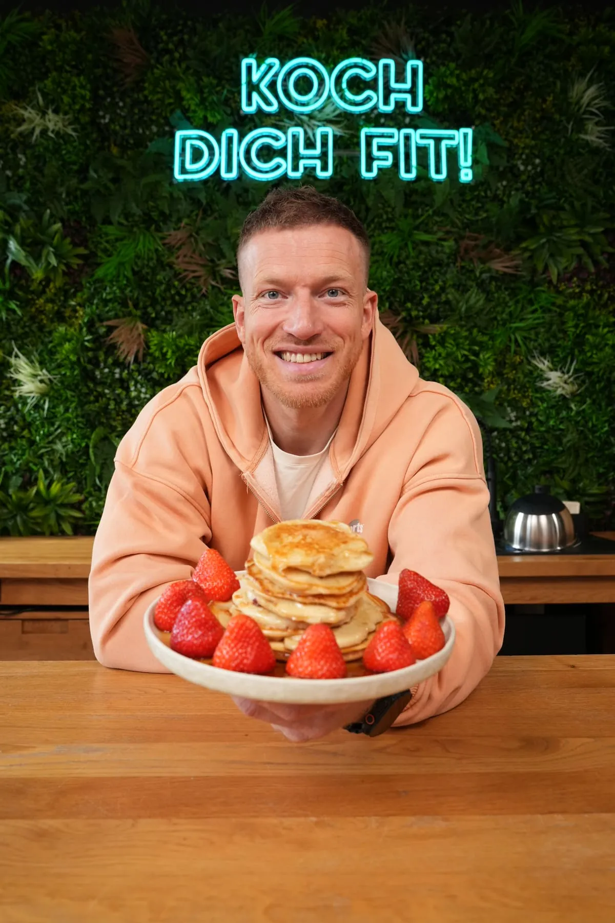 Kay Jaster in seiner Küche mit einem Teller Pancakes mit frischen Erdbeeren